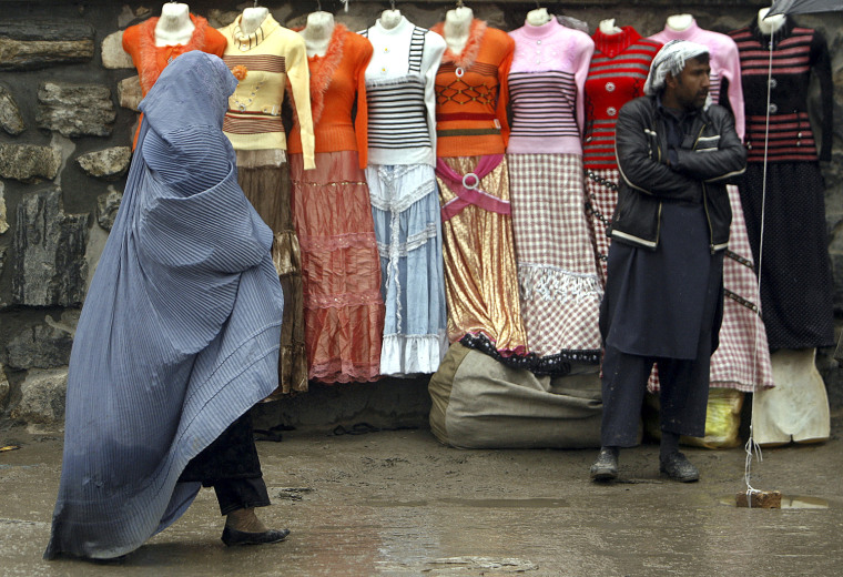 Image: An Afghan woman walks past mannequins displaying women's clothing for sale, along a street in Kabul